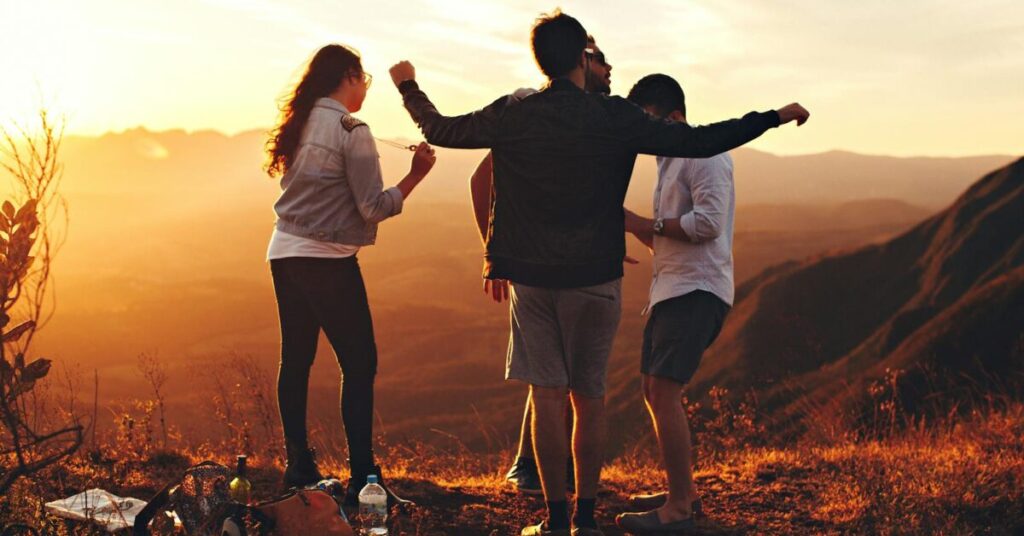 Joyful group of young adults enjoying a sunset view in a mountainous landscape in Brazil.
